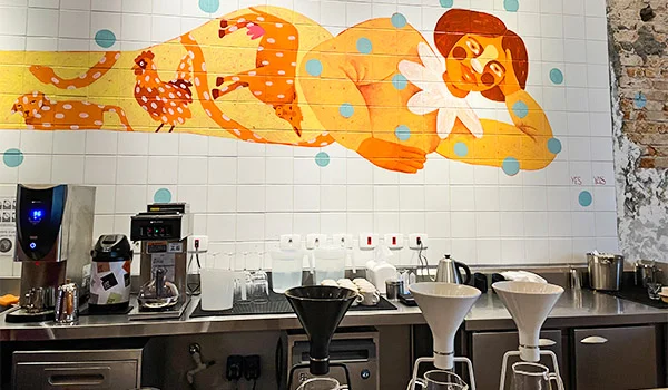 Foto do balcão da Cafeteria Cafetina com painel em azulejos de uma figura feminina com corpo de animal.