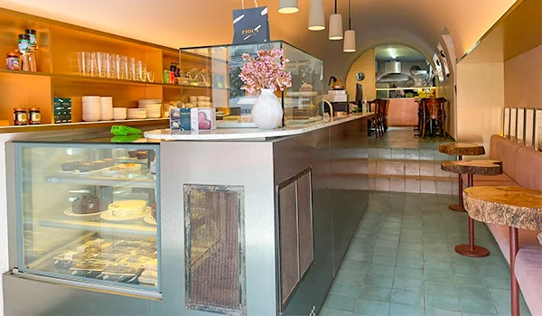 Foto da Doceria Fioca em Santa Cecília, onde aparece vitine com produtos, bancos e mesas.