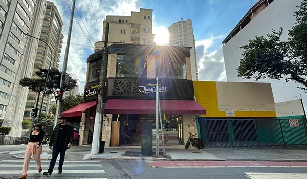 Foto do Jhony´s Bar na esquina da Rua Albuquerque Lins com Alameda Barros, onde aparece um casal atravessando a rua. Um dos Bares Santa Cecília.