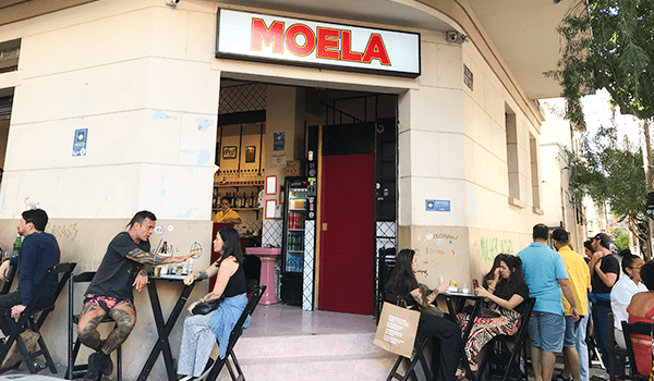 Foto da frente do Moela, com clientes em mesas na calçada, um dos bares da Santa Cecília que está na moda.