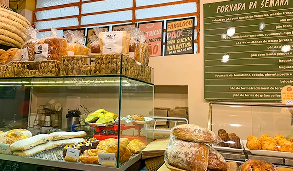 Imagem de uma padaria mostrando uma variedade de pães artesanais e produtos de panificação fit, destaque para pão caseiro e alimentos naturais.