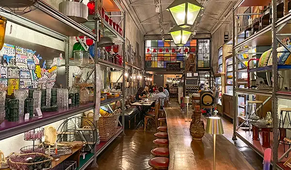 Ambiente acolhedor de loja de decoração com prateleiras cheias de objetos vintage e iluminação suave, ideal para quem busca móveis e itens de decoração exclusivos.