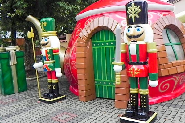 Decoração de Natal com soldadinhos artesanais ao lado de uma casa de estrutura de tecido que lembra uma cabine de presente natalino, ideal para fotos festivas. Natal em Campos do Jordão.