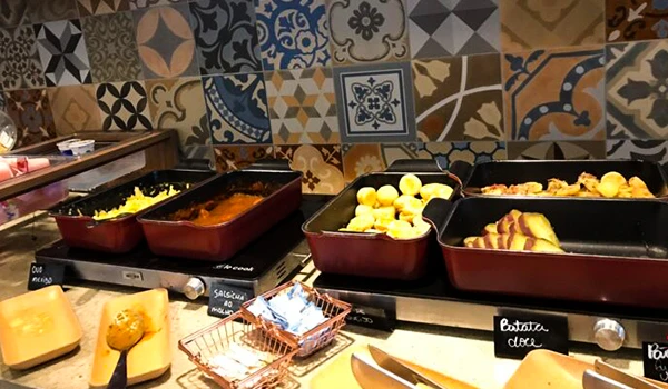 Buffet delicioso com pratos variados, incluindo batatas, pratos de carne e acompanhamentos frescos, ideal para apreciar na hora do café da manhã.