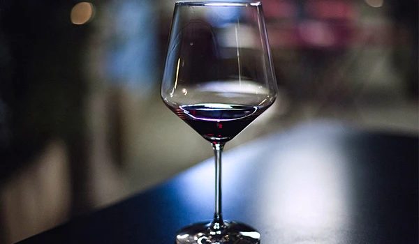 Taça de vinho tinto em um ambiente com iluminação suave e fundo desfocado, transmitindo elegância nas vinícolas de Punta del Este.