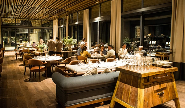 Ambiente elegante de restaurante com mesas preparadas para jantar, clientes felizes, decoração moderna e iluminação aconchegante.