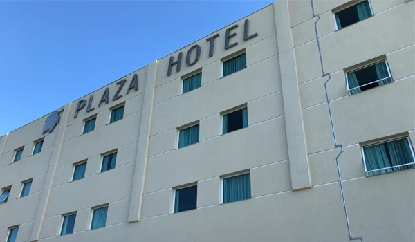 Fachada do Plaza Hotel destacando seu sinalização no topo do edifício, com janelas visíveis sob o céu azul claro.