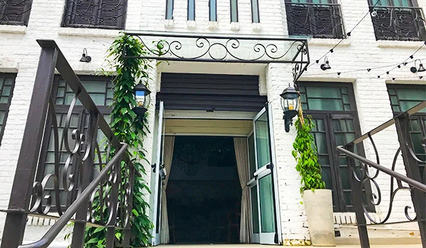Entrada de salão com portas de vidro abertas, decorada com plantas verdes em vasos brancos, na fachada.