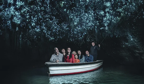 Foto de um barco pequeno com turistas dentro da caverna de Waitomo Caves na Nova Zelândia.