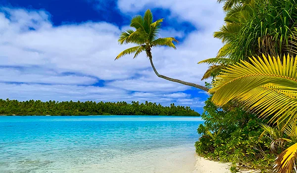 Paisagem de praia com coqueiros e mar azul na viagem para as Ilhas Cook.
