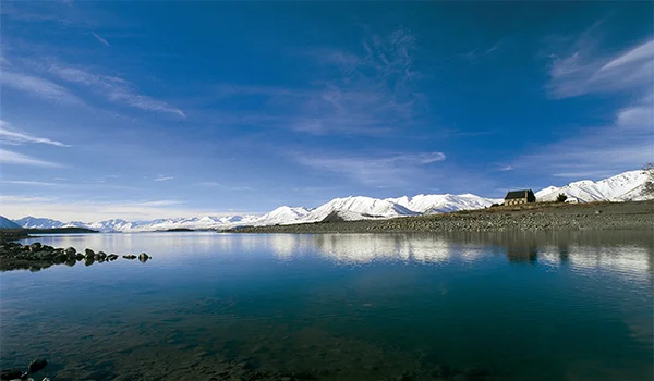 Foto do Lago Tepako cercado de montanhas nevadas na Ilha do Sul da Nova Zelândia.