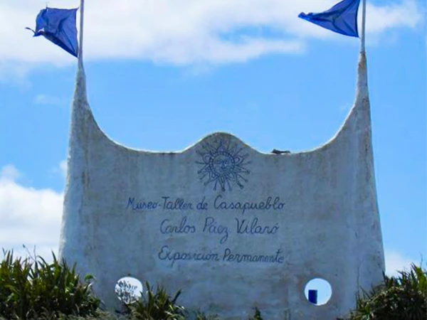Memorial no Museu Tallin de Casapueblo, com uma estrutura escultórica única e com bandeiras azuis ao vento, localizado na Uruguai. Destaca a exposição permanente do museu.