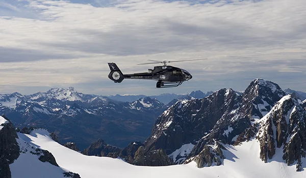 Foto de um helicóptero sobrevoando as montanhas nevadas do Mount Cook na Lua de Mel na Nova Zelândia.