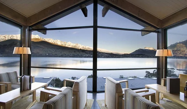 Foto do restaurante de um hotel na ILha do Sul da Nova Zelândia com linda vista da água e montanhas.