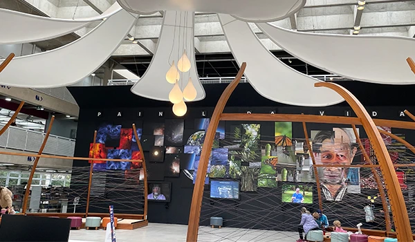 Fotografia de uma exposição de arte digital em um ambiente moderno, com várias telas exibindo imagens e pessoas observando as obras, ideal para promover tecnologia e inovação.