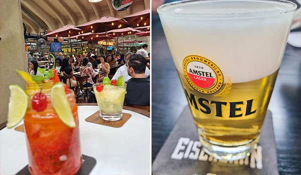 Imagem de uma área de bar no Mercadão de São Paulo, com várias pessoas apreciando drinques, com destaque para um copo de cerveja Amstel gelada na frente. Ambiente aconchegante com iluminação quente e decoração confortável.