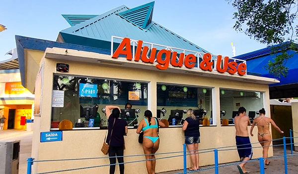 Imagem da loja Alugue & Use, oferecendo aluguel de itens de praia com pessoas aguardando atendimento.