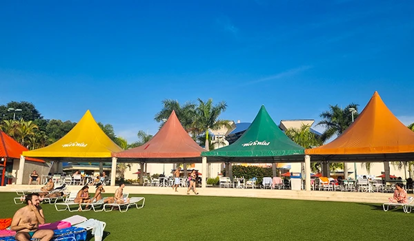 Imagem de área de lazer ao ar livre com tendas coloridas, perfeita para relaxar e aproveitar o sol com amigos e família em um ambiente descontraído, um dia no Wet´n Wild.