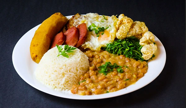 Prato típico brasileiro com arroz, feijão, couve, ovo frito, linguiça e farofa, ideal para quem aprecia a culinária local.