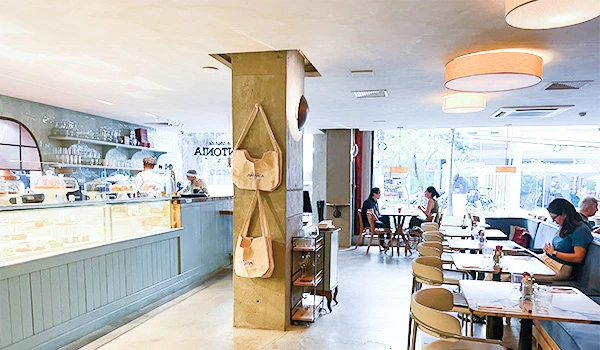 Ambiente moderno de cafeteria, destacando mesas e cadeiras, área de atendimento e decoração aconchegante. Ideal para relaxar e desfrutar de um café.