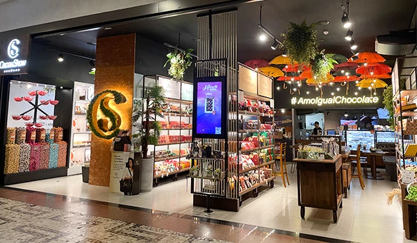 Loja moderna de chocolates com prateleiras repletas de produtos, decoração vibrante e iluminação aconchegante, ideal para amantes de chocolate.