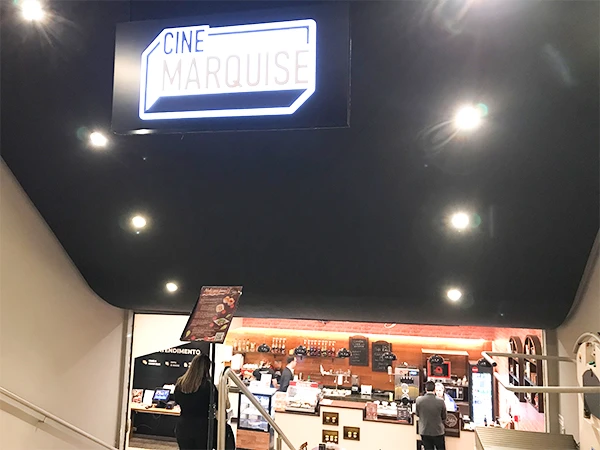 Entrada do Cine Marquês, um cinema moderno com um amplo balcão de comida e bebidas. Bustle de clientes na bilheteira e espaço acolhedor para assistir filmes.