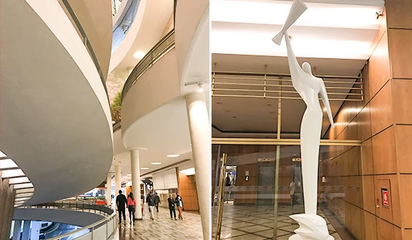 Imagem interna de um edifício moderno mostrando detalhes arquitetônicos e uma escultura destacada, ideal para atrair visitantes e turistas.