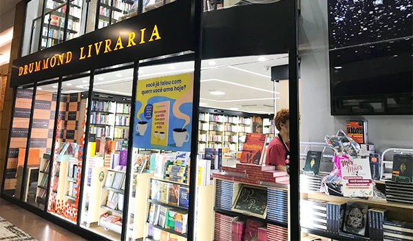 Imagem da Drummond Livraria, um local aconchegante para amantes de livros, com prateleiras repletas e uma decoração encantadora.
