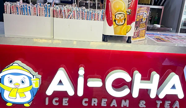 Foto do logo e balcão da loja Ai-Cha Ice Cream & Tea, onde se observa os canudos e detalhes dos produtos.