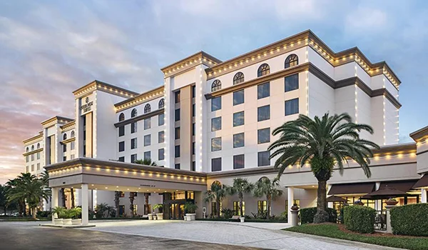 Foto do prédio Buena Vista Suites Orlando em estilo tradicional com fachada ornadas com coqueiros e jardim.