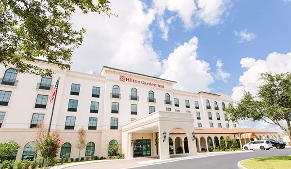 Foto do prédio do Hilton Garden Inn Winter Park, com estilo tradicional tendo no térreo fachada de colunas.