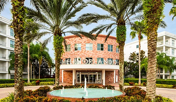 Foto da fachada estilo art decó do hotel Meliá Orlando, com tijolos a vista e palmeiras ao redor. Onde ficar em Orlando.