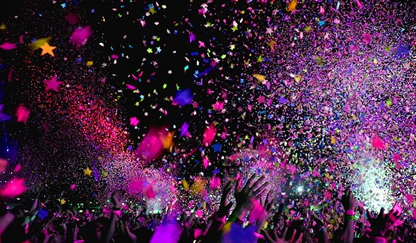 Foto de uma festa noturna com várias pessoas e confetes coloridos caindo, em Orlando.