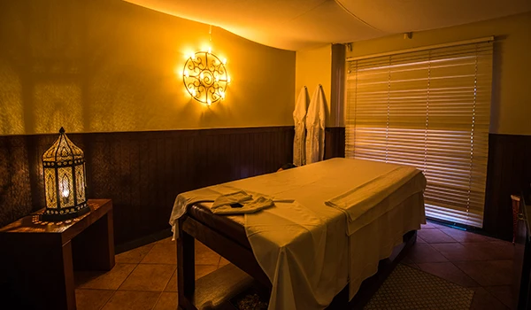 Sala de massagem relaxante com iluminação suave, mesa de massageiro e decoração aconchegante, ideal para tratamentos de bem-estar e terapia.