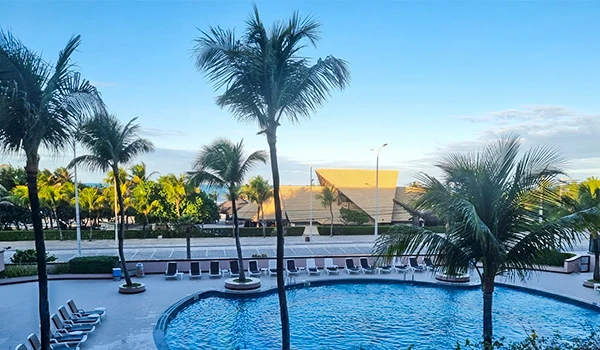 Piscina ao ar livre em clima tropical com várias palmeiras ao redor e ambiente relaxante, ideal para lazer e descanso.