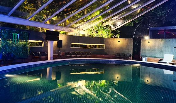 Foto noturna da área de piscina do Hotel Tivoli com teto de vidro e em tons de azul.