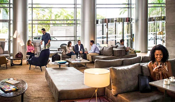 Foto do lobby do Grand Hyatt São Paulo onde aparece diversos clientes e vidraça com jardim a volta.