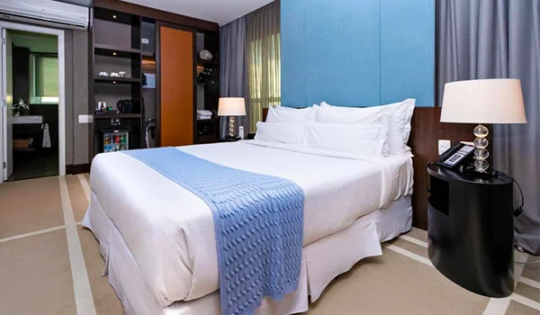 Foto do elegante quarto do Hotel Ca’d’Oro São Paulo, com cama e móveis finos.
