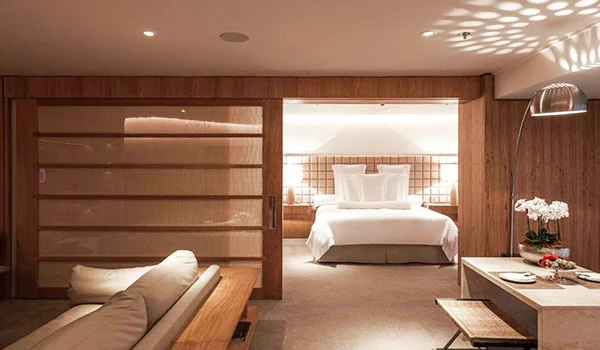 Foto de um elegante apartamento com cama e sofas do Hotel Emiliano, com decoração em madeira e sons claros.