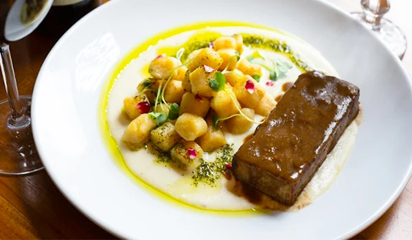 Prato de culinária brasileira com carne de sol, farofa de grão de bilo e vinagrete, disposto em um prato branco, perfeito para almoço.