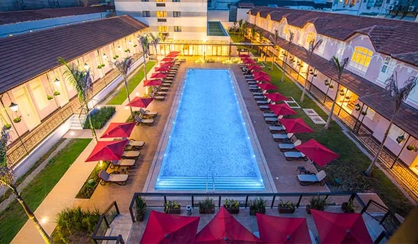 Imagem de uma piscina aquecida em um hotel com espreguiçadeiras e guarda-sóis vermelhos, criando um ambiente acolhedor para relaxamento e lazer.