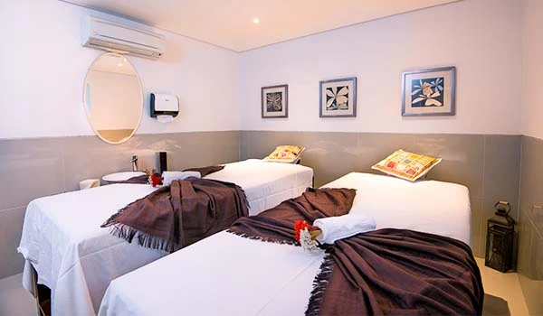 Quarto de hotel com duas camas de solteiro, decoração moderna, quadros na parede, ar-condicionado e iluminação suave, ideal para uma estadia confortável.