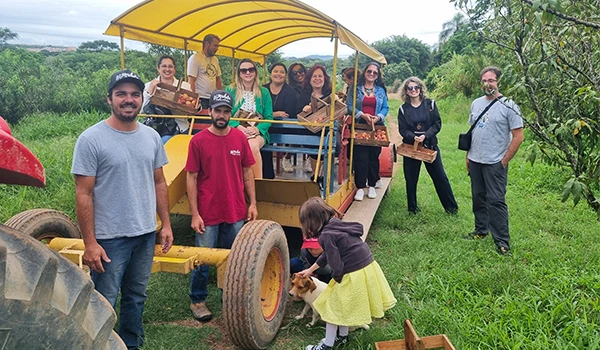 Grupo de pessoas sorrindo em um passeio agroecológico em um trator, explorando a natureza e aprendendo sobre sustentabilidade.