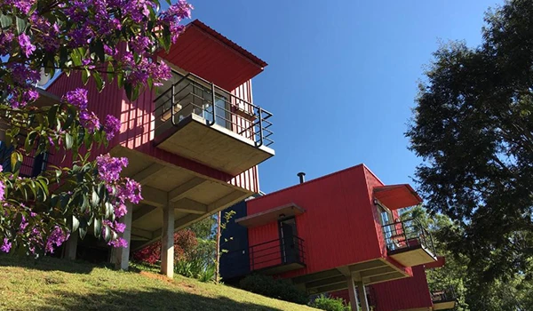 Foto de chalés com linda varandas, pintado em tom vermelho vivo, entre flores e árvores, em Cunha.