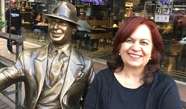 Deusa Rodrigues ao lado de uma escultura de Carlos Gardel em uma rua de Montevideu.