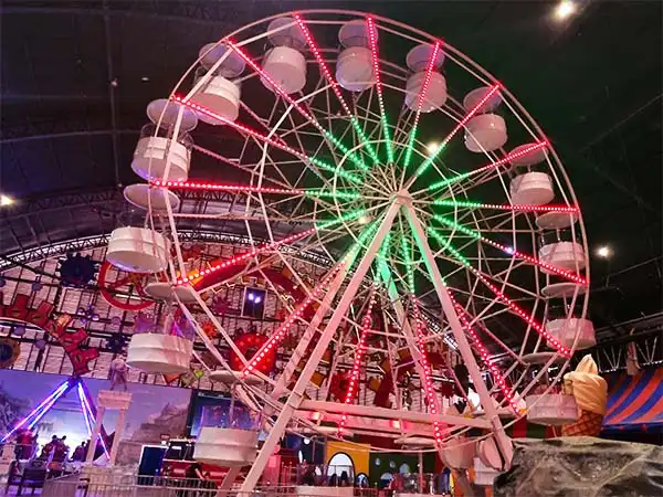 Roda gigante iluminada em parque de diversões, com assentos brancos e a estrutura decorada com luzes coloridas, criando um ambiente festivo.
