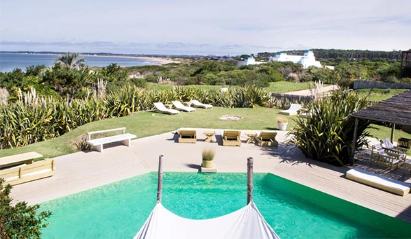Imagem de uma piscina ao ar livre com vista para a natureza, incluindo áreas de descanso e vegetação exuberante, ideal para momentos de lazer ao ar livre.