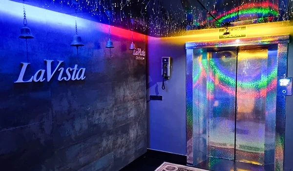 Imagem de um interior futurista com iluminação colorida e elevador com acabamento espelhado na LaVista, destacando uma atmosfera moderna e divertida.