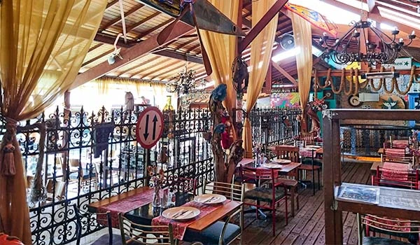 Foto do restaurante Dom Camillo com mesas e cadeiras e decoração de antiquário em Cotia.