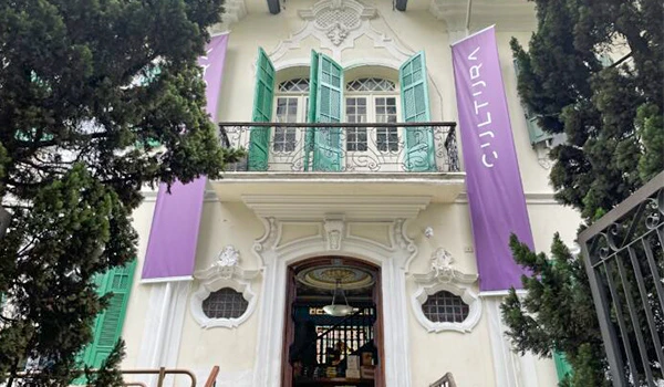Foto da fachada do casarão da Livraria Cultura em Higienópolis, com grandes chanelões de portas verdes, cercado de pinheiros.